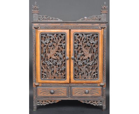 An early 20th century Chinese oriental Shanxi type cabinet having intricately carved pierced floral twin doors opening to rev