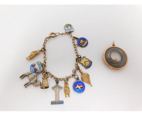 A silver charm bracelet and yellow metal circular mourning pendant. The mourning locket style pendant contains a lock of hair