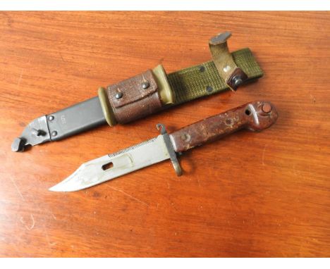 A WOODEN HANDLED MILITARY BAYONET, with serrated blade, a metal scabbard stamped SV132, and a leather and webbing strap 