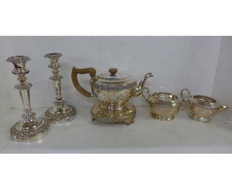A pair of plated candlesticks and a three piece plated tea service 