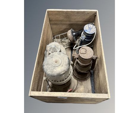 A vintage wooden crate containing three vintage oil lamps, a ship's lamp and an inspection lamp. (5)