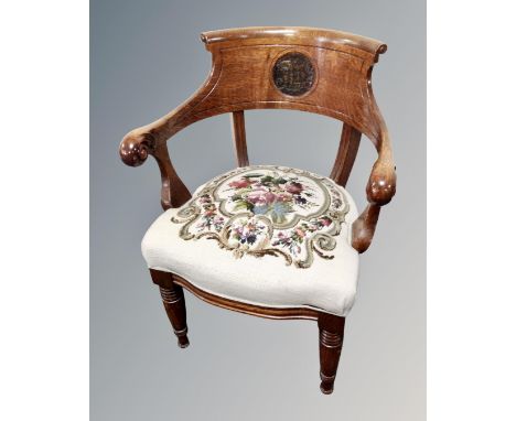 An oak elbow chair with tapestry embroidered seat and carved back.