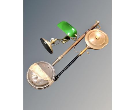A brass banker's lamp with green glass shade, together with two antique bedwarming pans.