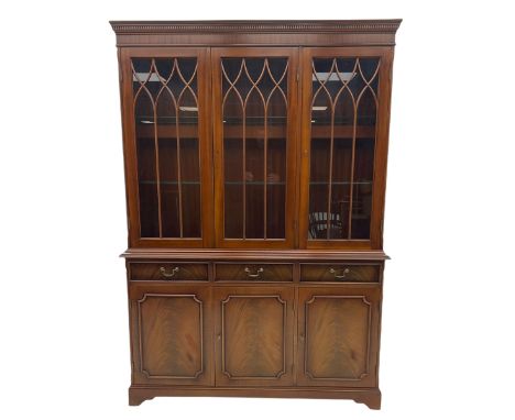 Georgian style mahogany bookcase on cupboard, dentil cornice over three glazed doors enclosing shelves, the lower section fit