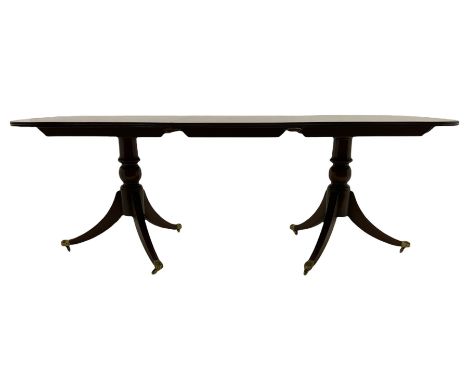 Regency style cross banded mahogany twin pedestal dining table, extending with additional leaf, on twin pillars each with thr