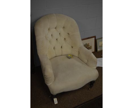 A Victorian cream upholstered easy armchair, the curved button back and out-swept arms above a serpentine seat-rail and raise