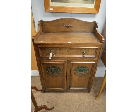 A 20th century oak music cabinet the rectangular top surmounted by a shaped gallery, above a single hinged frieze drawer and 