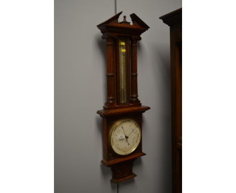 An early 20th century oak barometer, with swan neck pediment above a thermometer flanked by fluted pilasters, above a circula