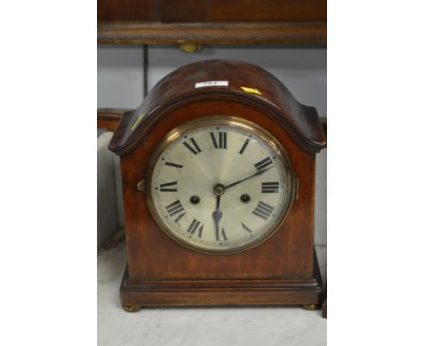 An Edwardian mahogany mantel clock striking a bell, with silvered dial and roman numerals contained with in a arched mahogany