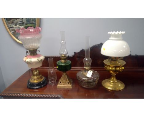 Four assorted oil lamps: brass, glass and porcelain, including a Sherwoods brass lamp with porcelain reservoir and pink and w