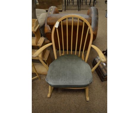 An Ercol light elm and beech rocking spindle back chair, with hooped back enclosing spindle spars above a shaped seat on tape