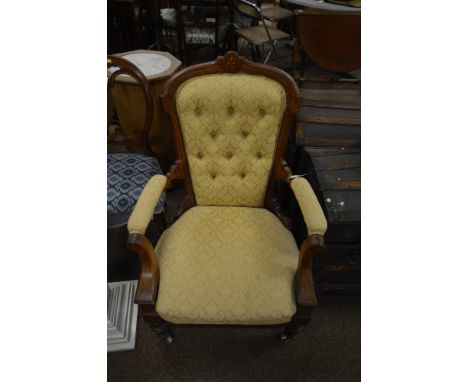 A Victorian walnut carved and inlaid armchair, upholstered in lemon fabric, the inlaid walnut frame enclosing a deep button b
