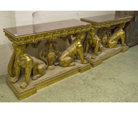 CONSOLE TABLES, a pair, gilt framed with glass and red lacquered tops on twin sphynx supports, 89cm H x 144cm W x 49cm D. (2)
