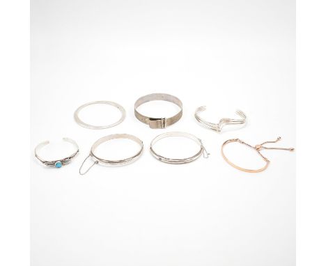 A collection of seven silver bangle bracelets. The lot to include two hinged bangles with rope twist borders, a textured bang