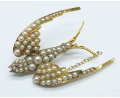 A yellow metal and seed pearl swallow brooch, with cabochon ruby eye, (tests as gold), lacking pearls safety chain a/f, 5g, 3