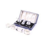 A silver round three piece cruet set and four napkin rings.