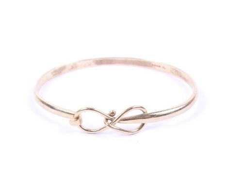 A vintage 9ct gold 'lovers knot' bangle. The front designed as an open figure-of-eight knot incorporating the hook-catch, hal