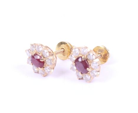 A pair of vintage ruby and diamond oval cluster stud earrings. Each centred with an oval mixed-cut ruby within a round brilli