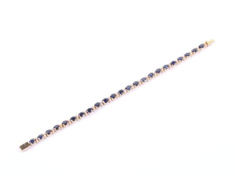 A vintage sapphire and diamond line bracelet. The 23 oval mixed cut sapphires spaced by pairs of small round brilliant diamon