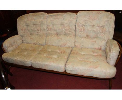 An Ercol mid-elm stick back three seater sofa, with fabric upholstered squab cushions on turned supports, width 185cm