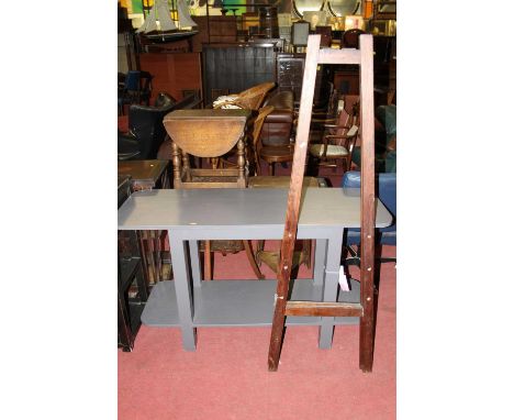 A contemporary grey painted round cornered two-tier side table, w.128cm; together with a stained pine artists easel (2)