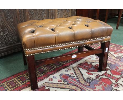 Brown leather footstool, the button seat raised on square legs and flattened stretchers