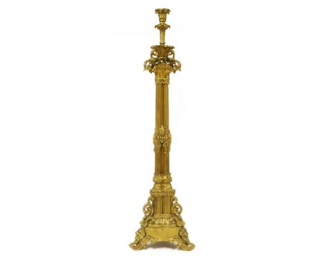 A large gilt metal candlestick, with pierced scrolling brackets and cluster column support on scrolling feet,83cm high