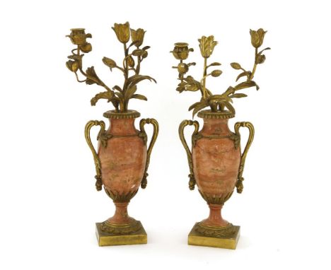 A pair of pink marble and ormolu candelabra, 19th century, each fitted with three floral branches within a twin-handled vase 