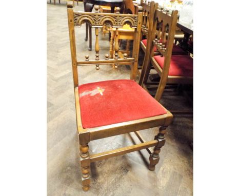 A set of six Ercol oak turned spindle back dining chairs with red upholstered seats