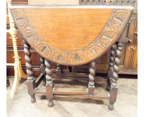 An oval oak gate leg table with carved edge standing on barley twist legs 2'6 wide 