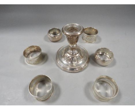 A hallmarked silver squat candlestick together with six assorted silver napkin rings 