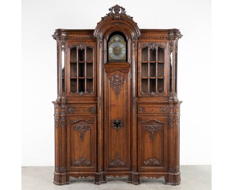 An antique display cabinet with a standing clock, Liege, Belgium. Sculptured oak, 19th century. Clock with moon phase, 18th c