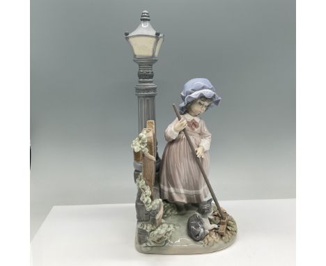This Lladro porcelain figurine, titled Fall Clean Up and numbered 01005286, depicts a young girl in a bonnet holding a broom 