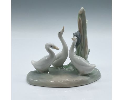A charming Nao porcelain figurine depicting three ducks gathered near reeds. This glossy finish porcelain piece features deli