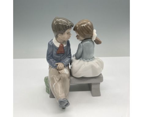 Charming porcelain figurine by Nao, a division of Lladro, depicting a young girl seated gracefully on a rock with a delicate 