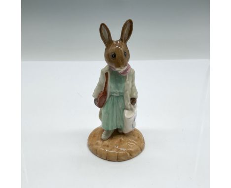 This charming figurine, titled Shopper Bunnykins, stands 4.75"H and is part of the Royal Doulton Bunnykins series. Crafted in
