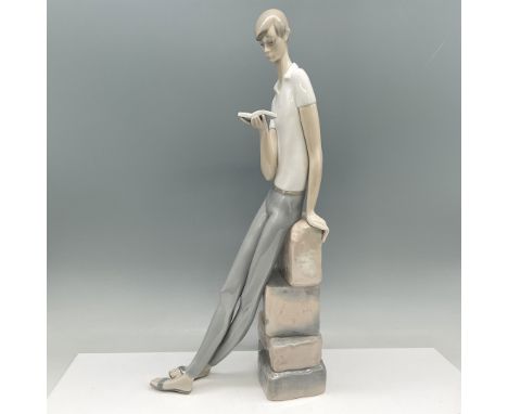 Charming Lladro porcelain figurine titled Boy Student, featuring a young man seated on a stack of stone blocks, deeply engros