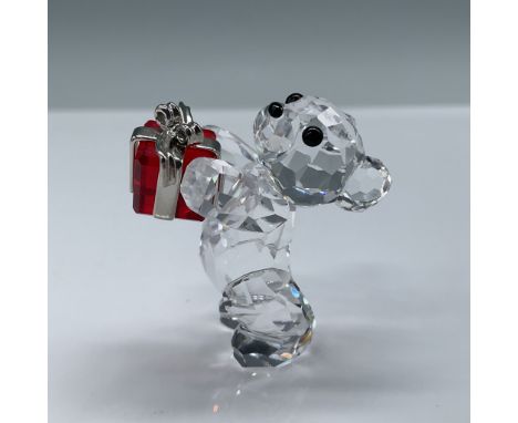 Swarovski Crystal figurine of a Kris Bear holding a vibrant red gift adorned with silver-tone accents. This charming crystal 