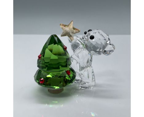 This Swarovski Kris Bear Christmas Annual Edition 2018 figurine features the charming Kris Bear standing beside a green facet