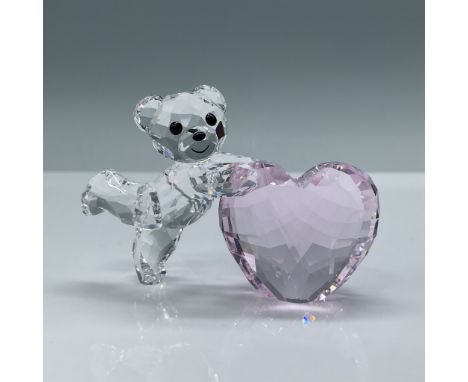 This Swarovski crystal figurine features a charming Kris Bear holding a faceted pink heart, symbolizing love and affection. P