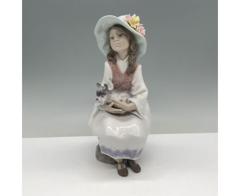 This Lladro porcelain figurine, titled Daydreams (01006400), depicts a serene young girl seated on a rock, holding a small do