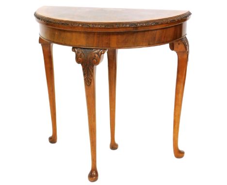 A Georgian style mahogany and walnut demi-lune fold over card table, with a green baize interior, raised on slender cabriole 