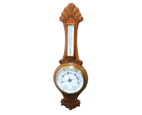 A Victorian oak cased wheel barometer, with a circular white enamelled dial, and thermometer, the case of carved foliate form