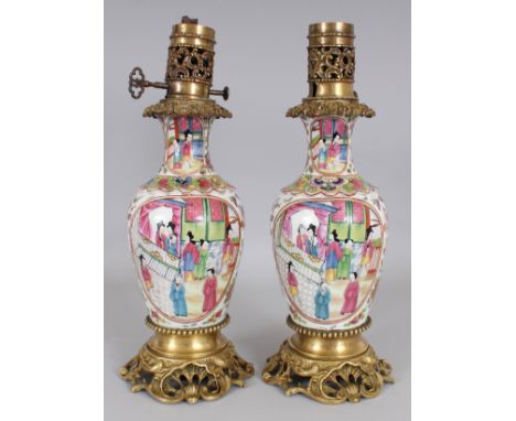 A PAIR OF CHINESE CANTON STYLE PORCELAIN VASES, mounted with oil lamp fittings and pierced ormolu stands, 15.5in high overall