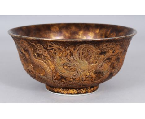 AN UNUSUAL CHINESE MOULDED PORCELAIN DRAGON BOWL IMITATING GILT SPLASHED BRONZE, the sides decorated in relief with three dra