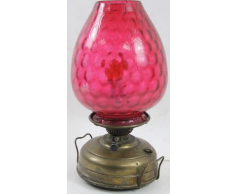 An early 20thC brass lamp, with textured ruby glass shade, 51cm H.