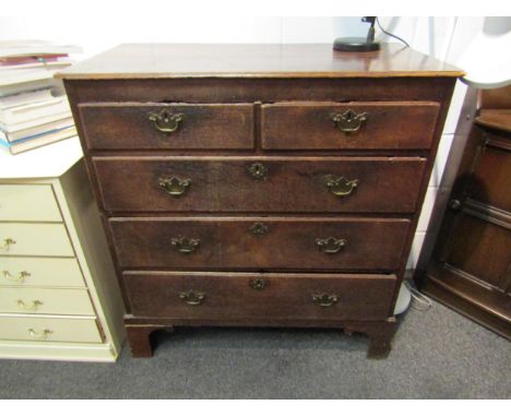 A Georgian oak country chest of two short over three long graduating drawers, brass shaped handles, on shaped bracket support