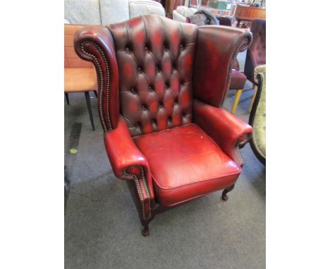 A Chesterfield style red leather two seater sofa together with a wingback armchair on cabriole legs (2) 