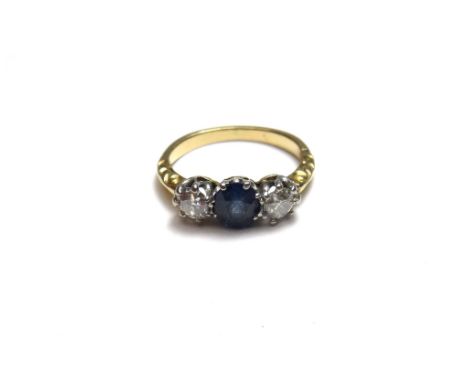 A gold, sapphire and diamond set three stone ring, claw set with the oval cut sapphire at the centre, between two cushion sha