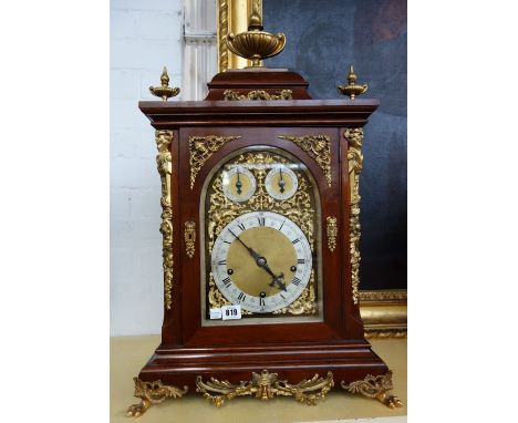 A mahogany cased triple train mantel clock, late 19th/early 20th century, with urn surmount over an ornately ormolu embellish